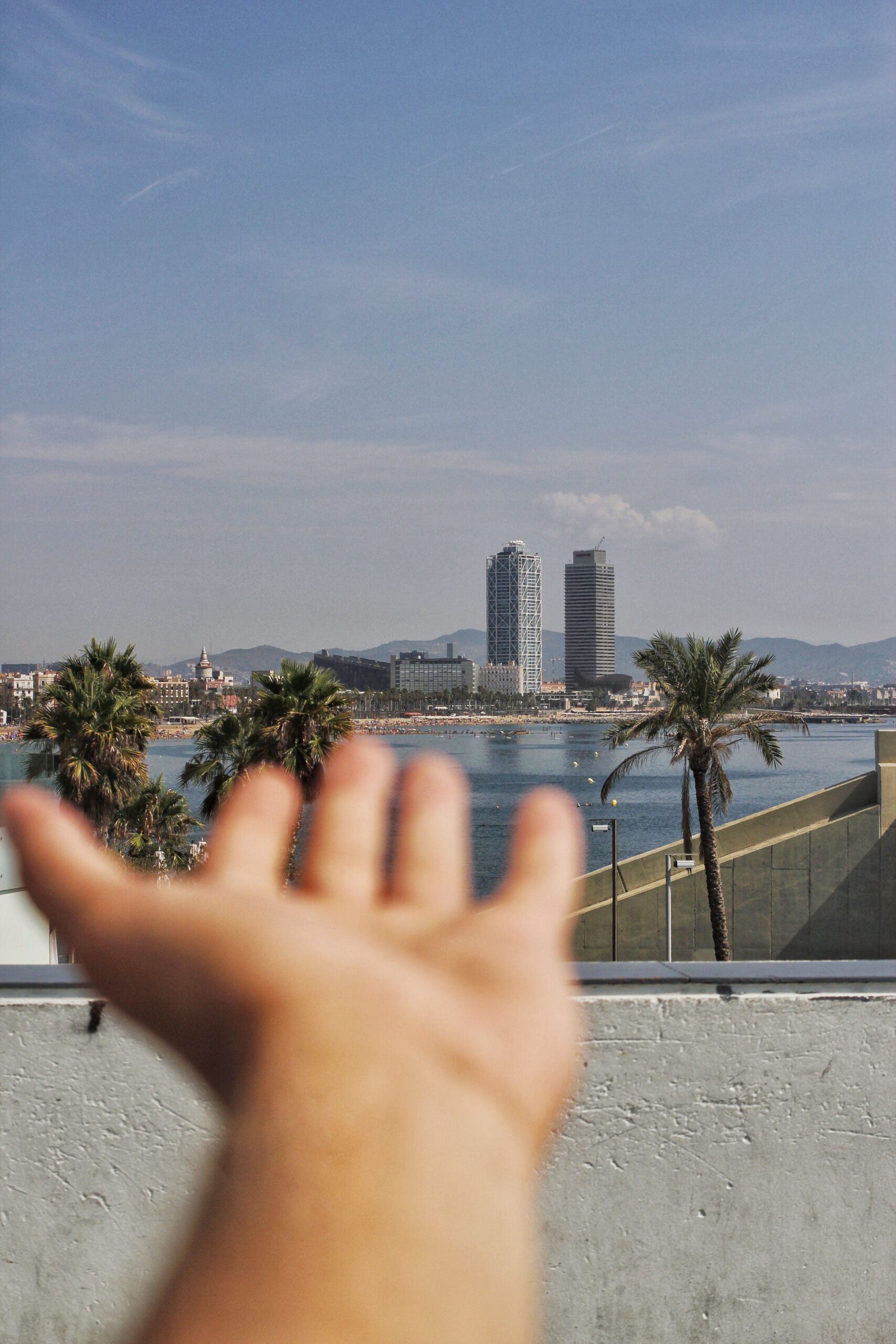 Fotografía de una mano y un paisaje costero.